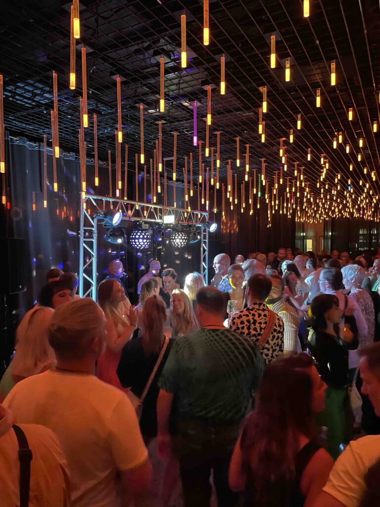 Stimmungsvolle After Work Party in einem stilvollen Ambiente mit modernen Hängelampen und tanzenden Gästen, die zur Musik feiern.