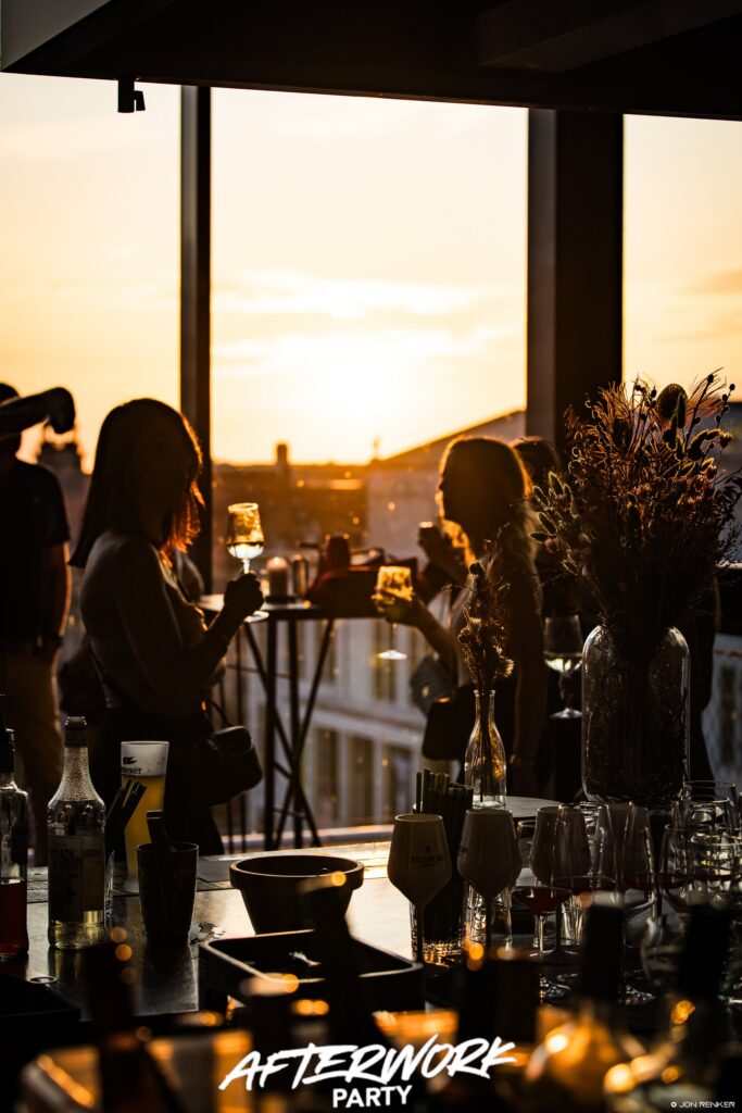 Gäste mit Getränken genießen den Sonnenuntergang bei der After Work auf der Rooftop-Bar des FELIX